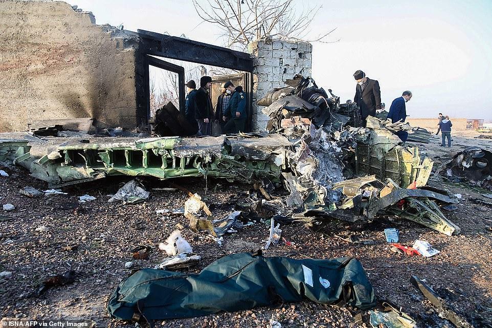 People stand near the wreckage after a Ukrainian plane carrying 176 passengers crashed near Imam Khomeini airport